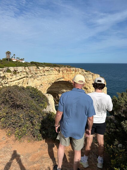 Two people standing on a rocky cliff overlooking the ocean. 3