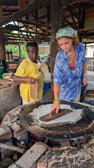 Two people at a cooking station with a large griddle and a fire beneath it. 2