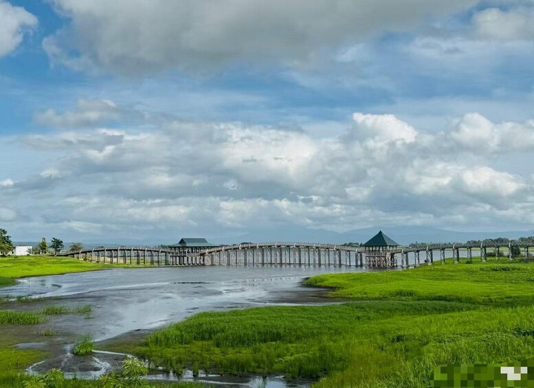 A coastal landscape with a pier extending into the water, surrounded by green fields and a cloudy sky. 1