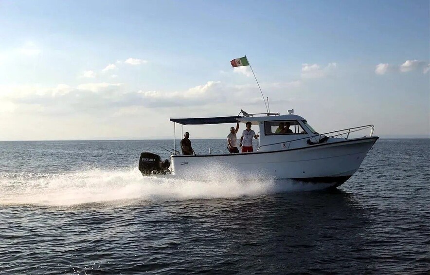 A white boat with a flag, moving through calm water under a clear sky. 5