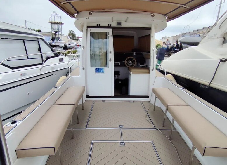 An open doorway to a boat's interior with a steering wheel, a small table, and a bench. 3