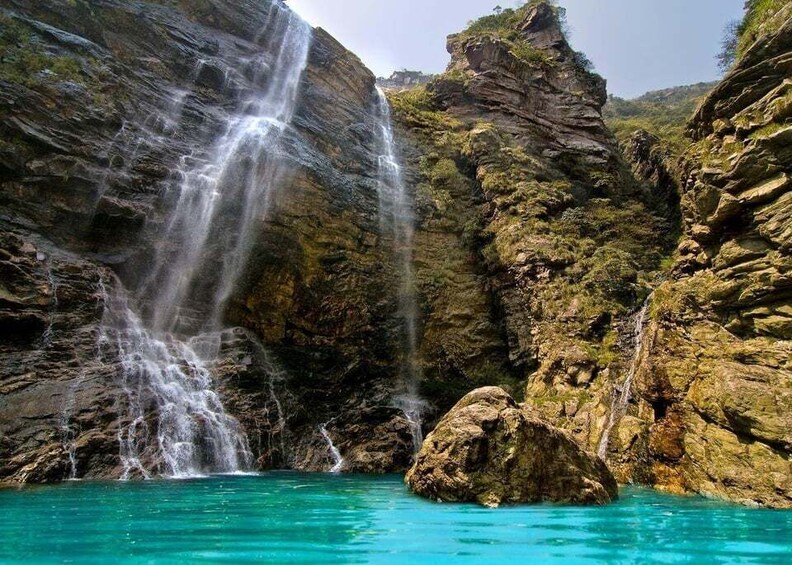 A waterfall cascading into a turquoise pool surrounded by rocky cliffs. 4
