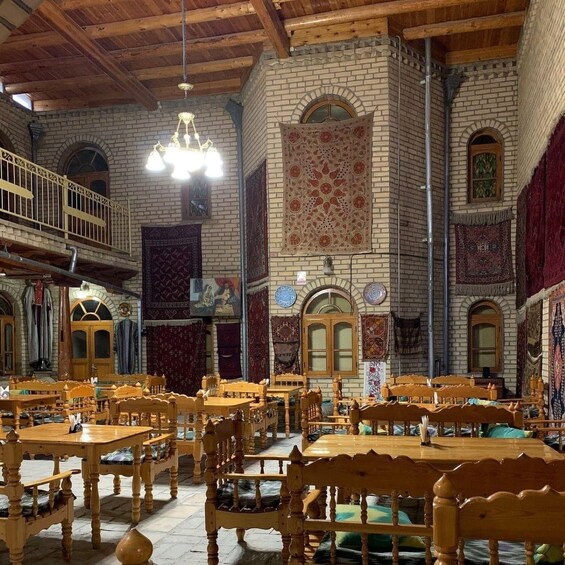 A spacious hall with wooden tables and chairs, a balcony, and ornate wall decorations. 5