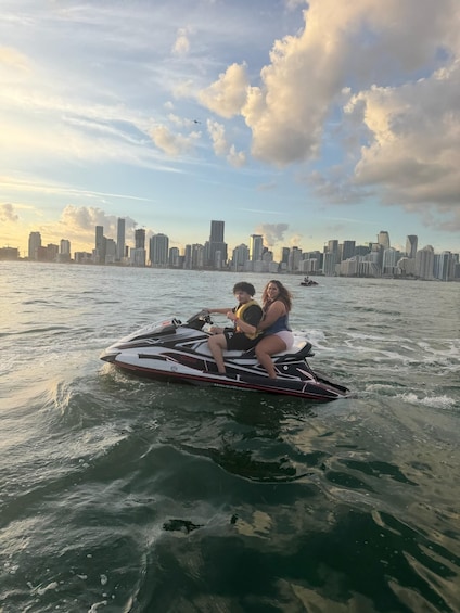 Two people on a jet ski with a city skyline in the background. 2