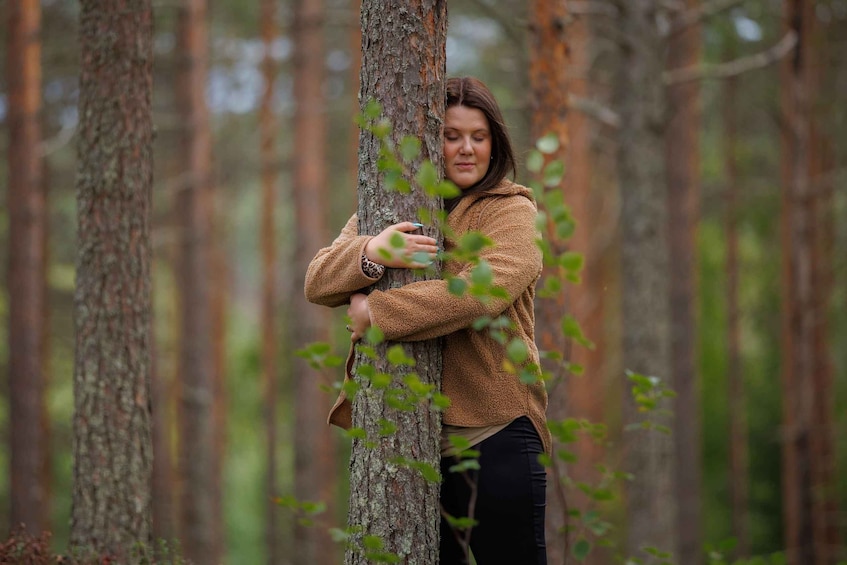 A person hugging a tree in a forest. 5