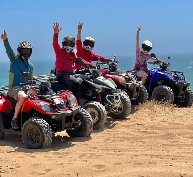 A group of people on ATVs on a sandy beach with the ocean in the background. 4