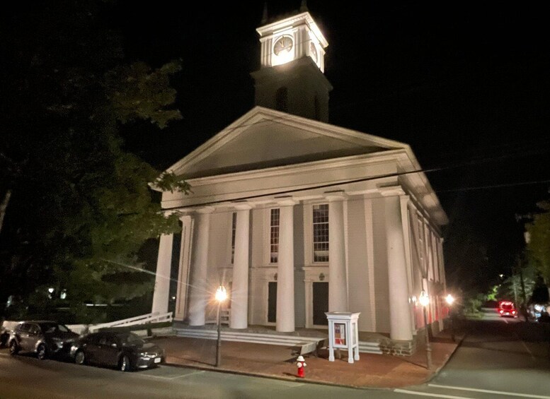 A large, white building with columns and a clock tower at night. 3