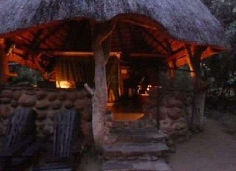 A rustic thatched-roof hut with a wooden door and a stone wall. 5
