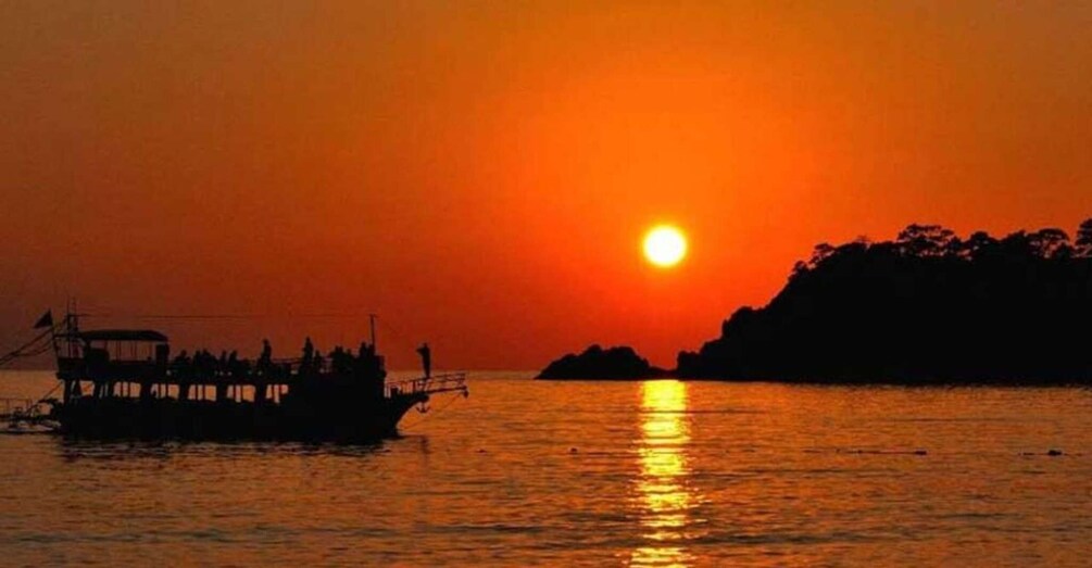 A sunset over water with a boat and a distant island. 5