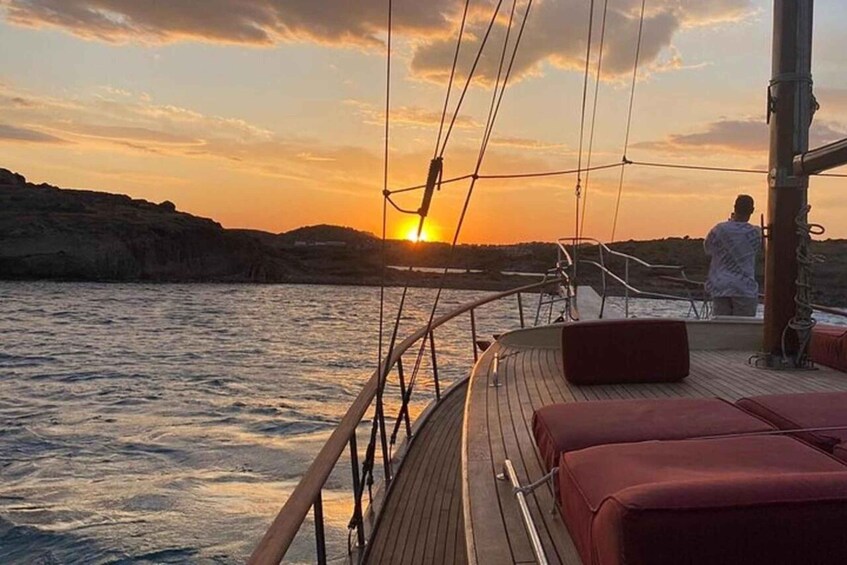 A sunset on a calm sea with a boat's deck and red cushions. 2