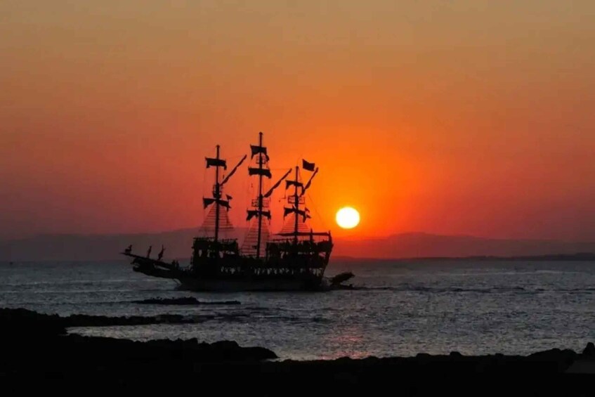 A ship silhouetted against a sunset with the sun near the horizon. 4