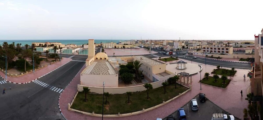 A coastal cityscape with a prominent roundabout, a central building with a dome, and a view of the sea. 5