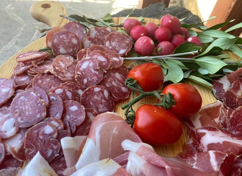 A variety of cured meats and fresh tomatoes on a wooden board. 2