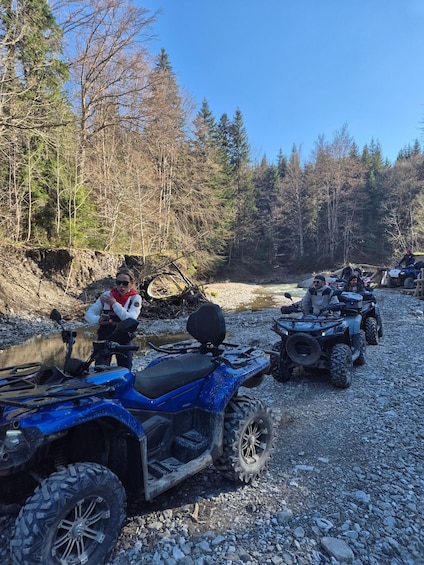 A group of ATVs parked on a gravel path in a forested area. 1