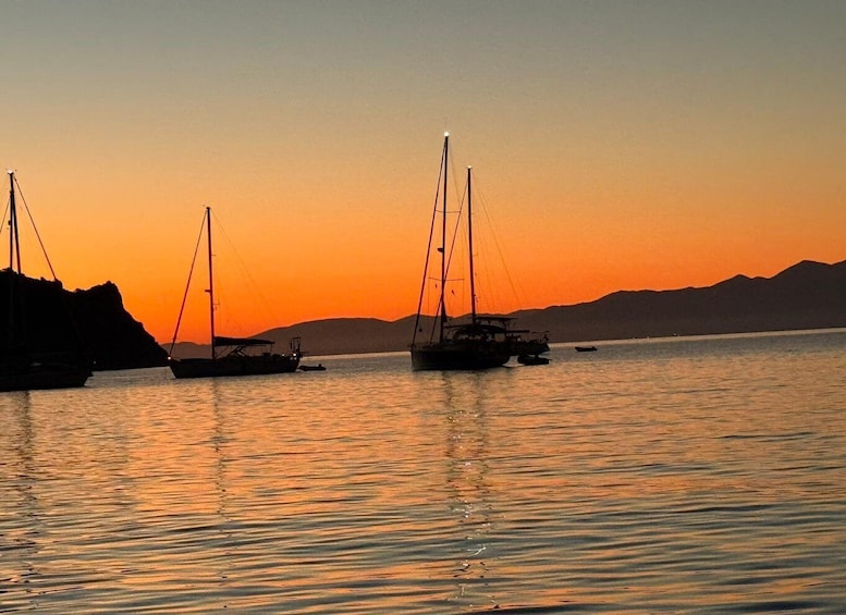 Sailboats anchored on calm water during sunset with mountains in the background. 4