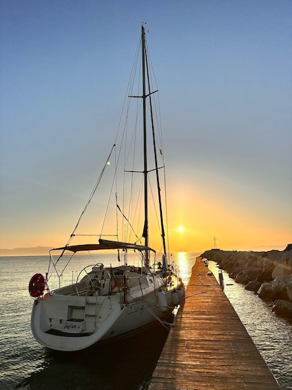 A sailboat docked at a wooden pier during sunset. 5