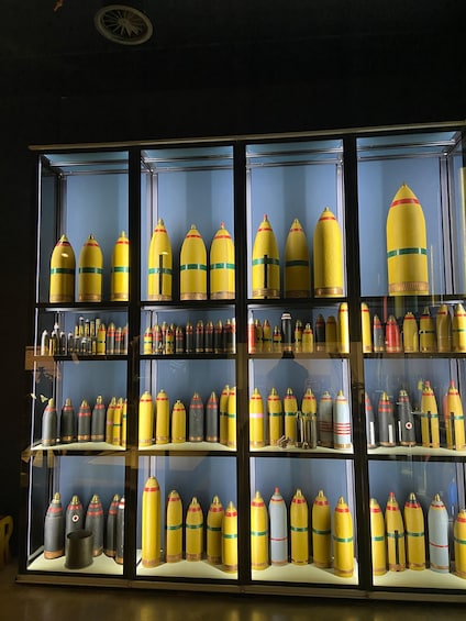 A display of various shaped and colored bottles, likely for decorative or collectible purposes, arranged in a glass case. 3