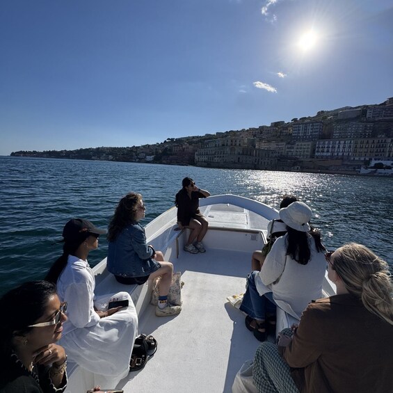A group of people on a boat, facing a coastal cityscape with buildings along the shore. 4