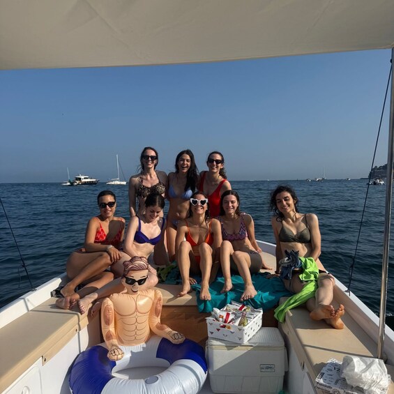 A group of people on a boat with the sea and other boats in the background. 2