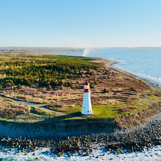 A lighthouse on a rocky coastline with a forested area in the background. 3