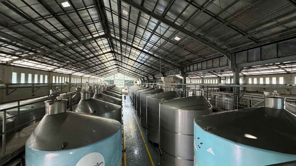 A large industrial facility with rows of large tanks and a high ceiling with metal beams. 2