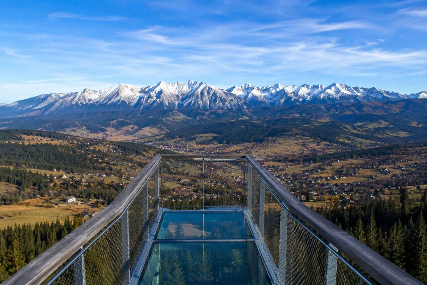 A glass-bottomed viewing platform overlooking a mountainous landscape with snow-capped peaks. 2