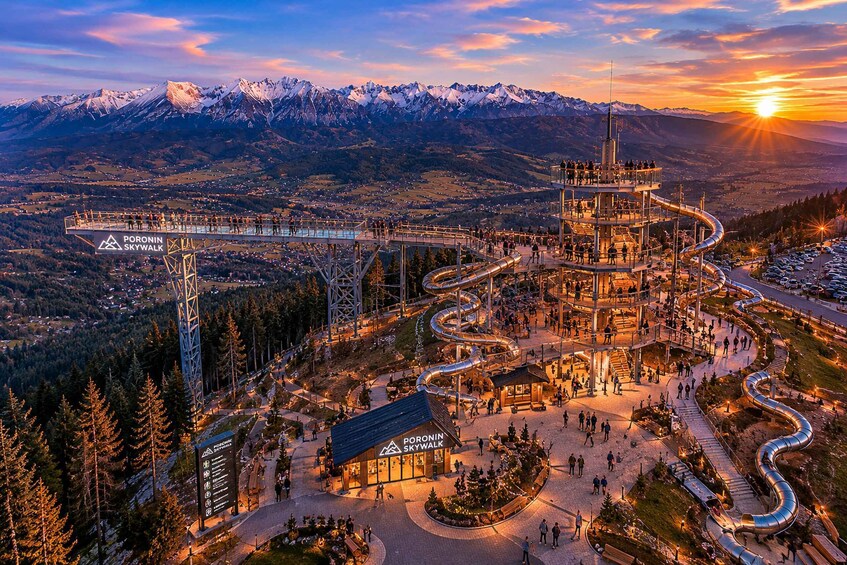 A mountainous landscape with a ski lift and a viewing platform at sunset. 1