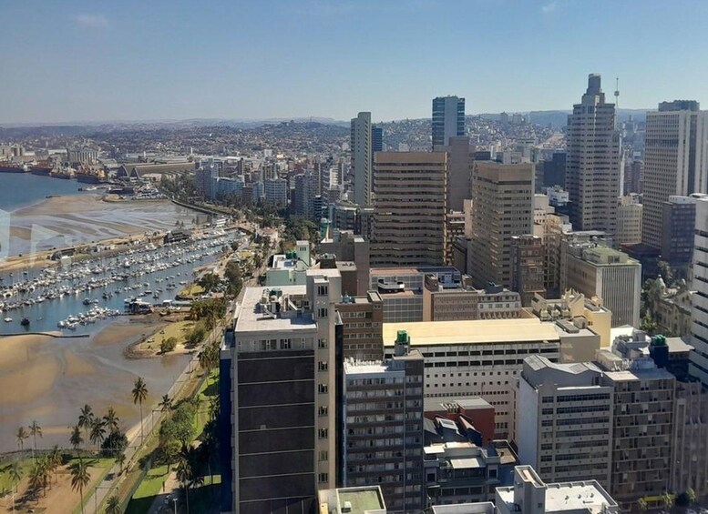 A coastal cityscape with high-rise buildings, a marina, and a beach. 1