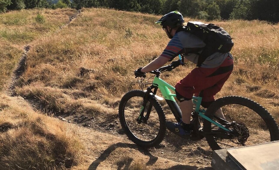 A person riding a mountain bike on a dirt trail in a grassy area. 3
