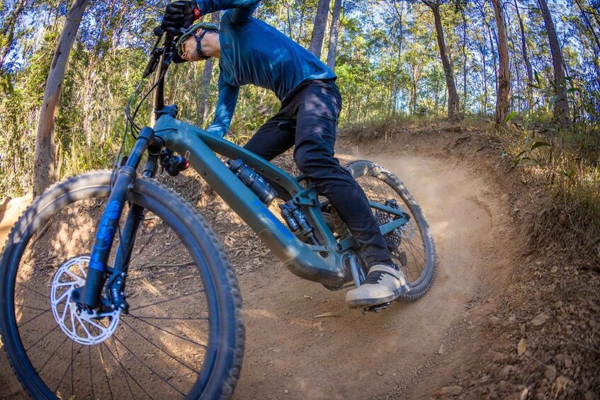 A person riding a mountain bike on a dirt trail in a forested area. 2