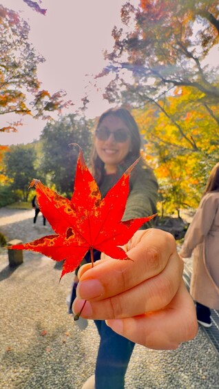 A person holding a red maple leaf. 1