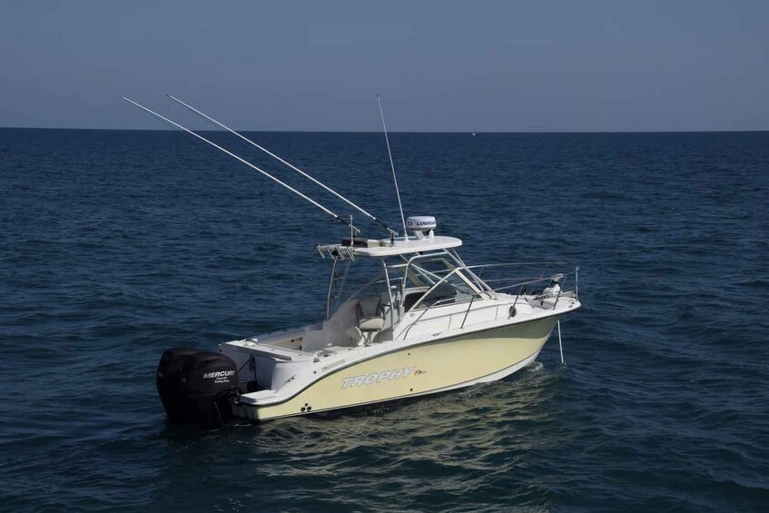 A white fishing boat named 'TROPHY' with a Mercury outboard motor on calm blue water. 4