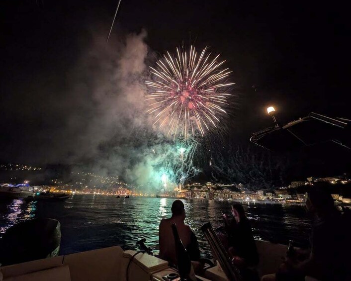 A boat with people watching fireworks over a city skyline at night. 5