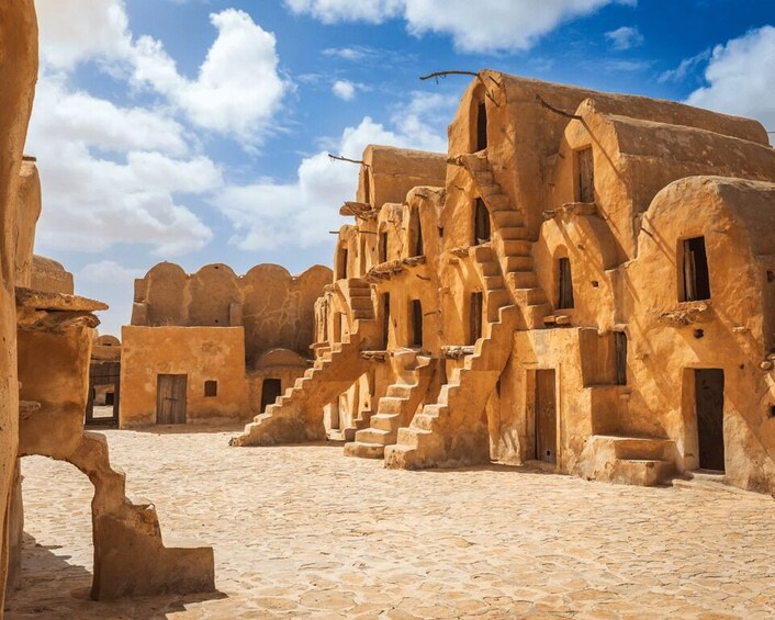A historic stone courtyard with traditional architecture, including arched doorways and a central staircase. 2