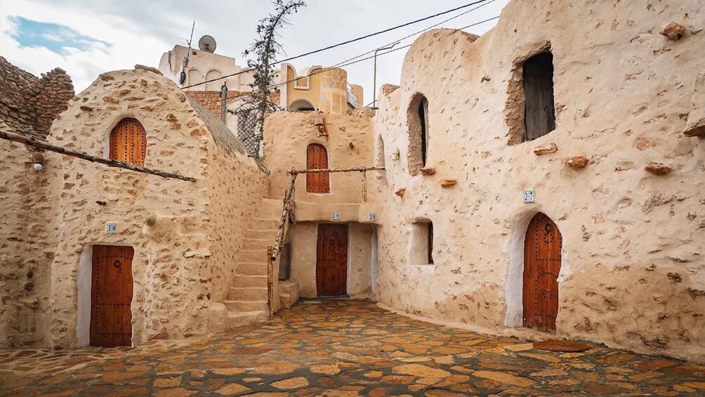 A narrow alley with traditional stone buildings, wooden doors, and a cobblestone path. 5