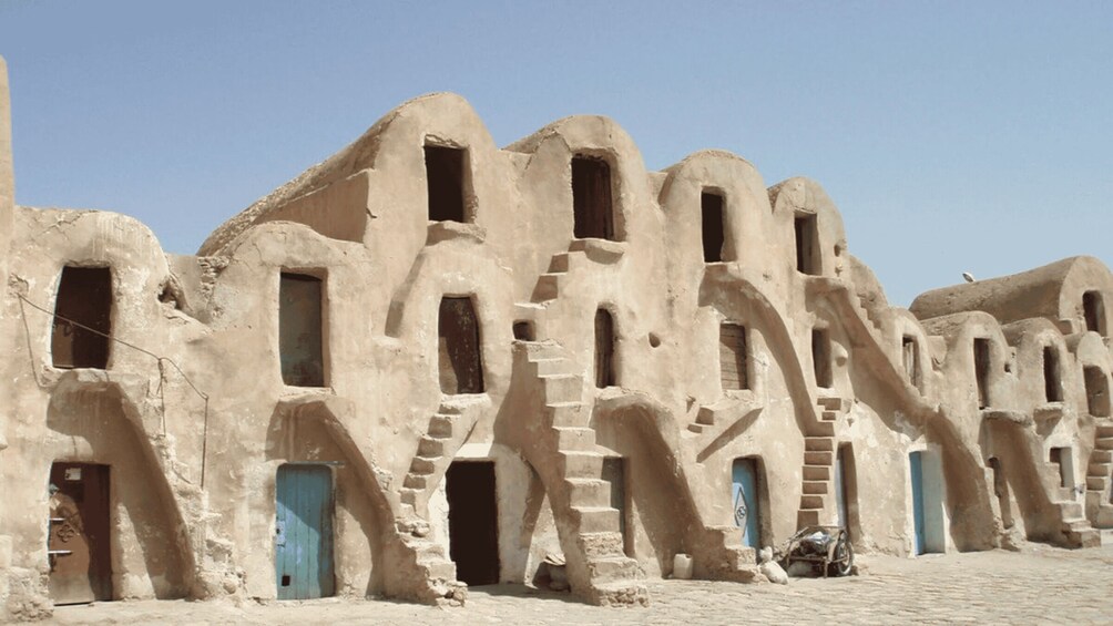 A row of traditional mud-brick houses with arched doorways and windows. 3