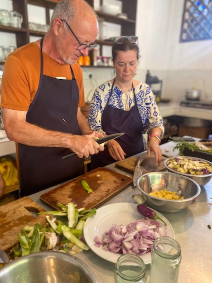 Two people in a kitchen preparing food, with vegetables and bowls on the counter. 4