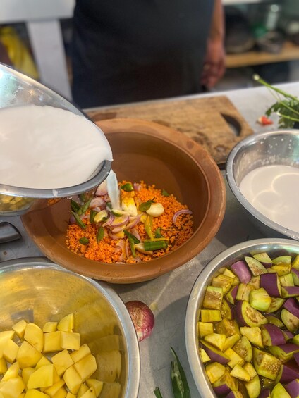 A person pouring a white liquid into a bowl containing lentils, onions, and green vegetables. 3