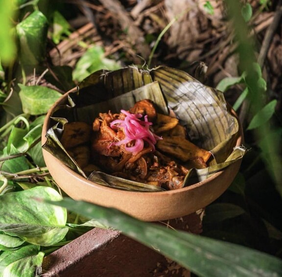 A traditional dish in a woven basket, surrounded by greenery. 3