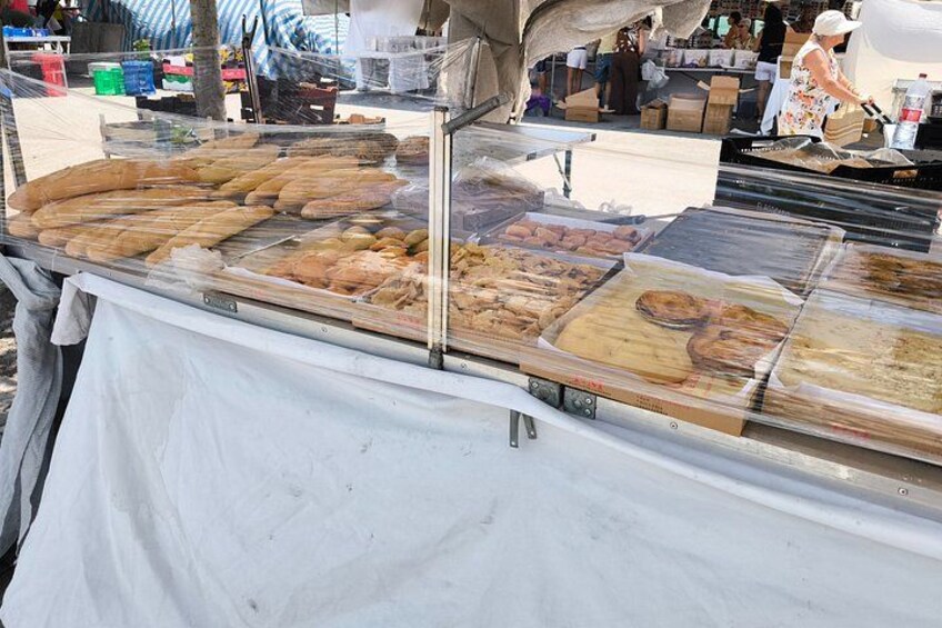 A food stall with various baked goods and pastries displayed in a glass case. 2