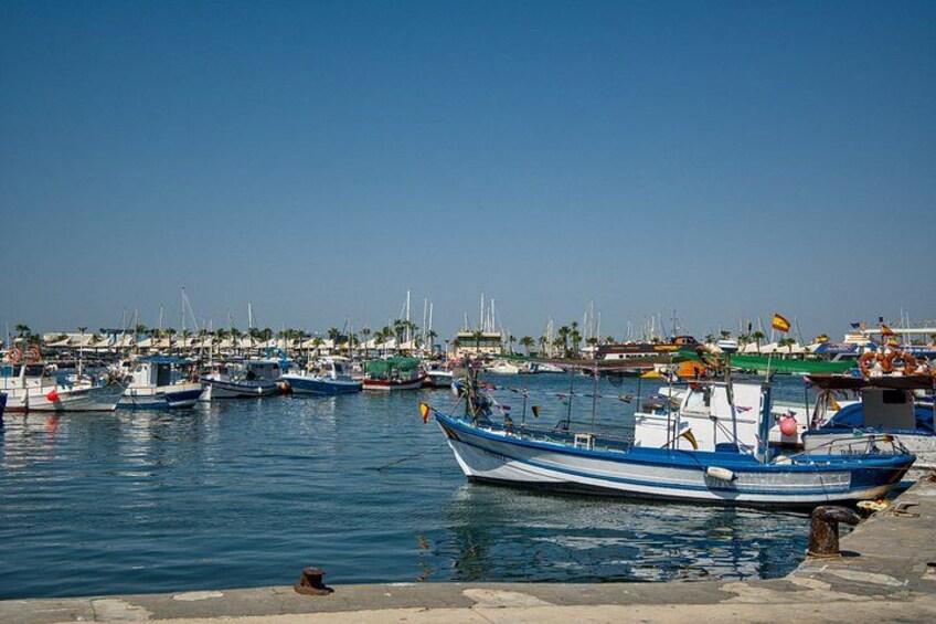 A harbor with multiple boats docked, calm water, and a clear sky. 2