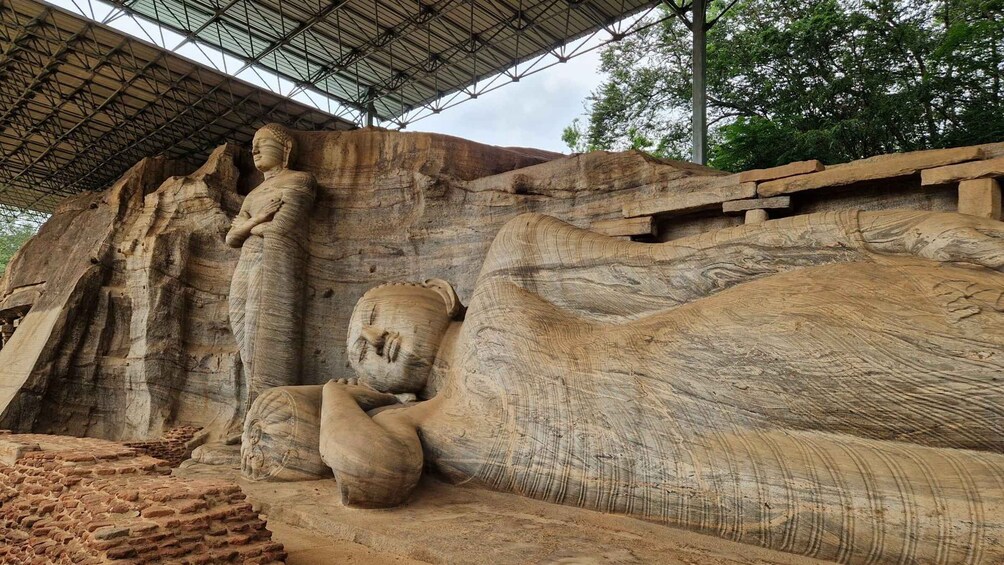 A large rock formation with carved statues and a covered walkway. 1