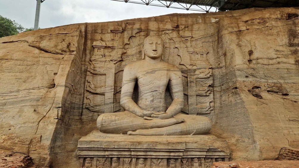 A large seated Buddha statue carved into a rock face. 2
