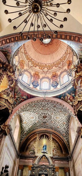 An ornate church interior with a large dome, intricate ceiling artwork, and a central statue. 5