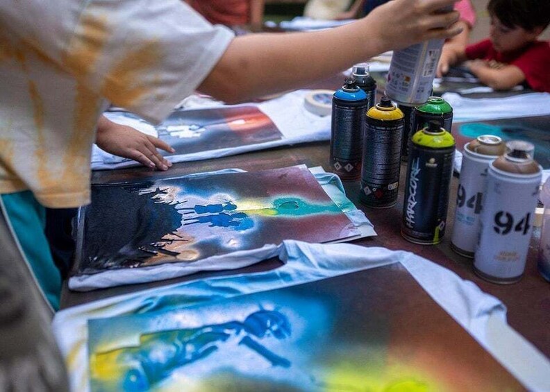 A person painting on a t-shirt with spray paint cans. 4