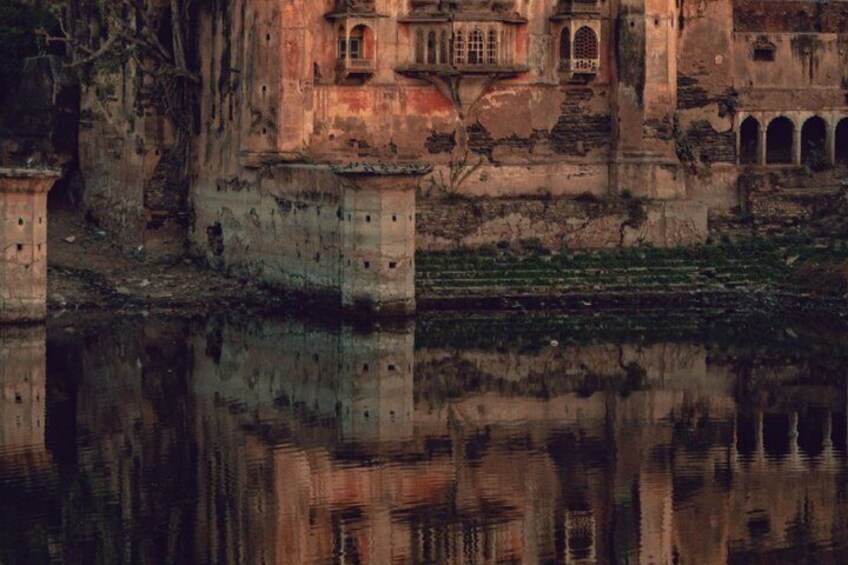 An ancient, dilapidated building with arched windows and a reflection in the water. 4