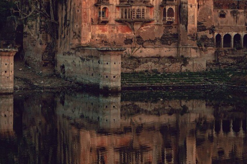 Un bâtiment délabré, doté de fenêtres en arc de cercle, dont le reflet se mire dans l’eau. 4