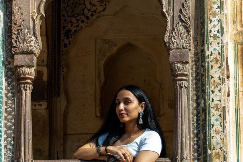 A person seated in an ornate architectural setting with detailed carvings and a patterned archway. 3
