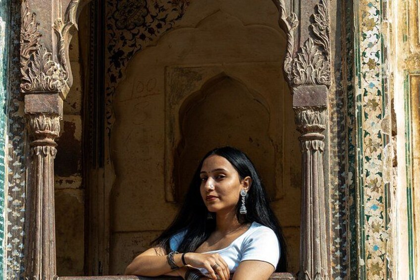 Une personne est assise dans un portail richement décoré, orné de sculptures complexes et adossée à un mur aux motifs élaborés. 3