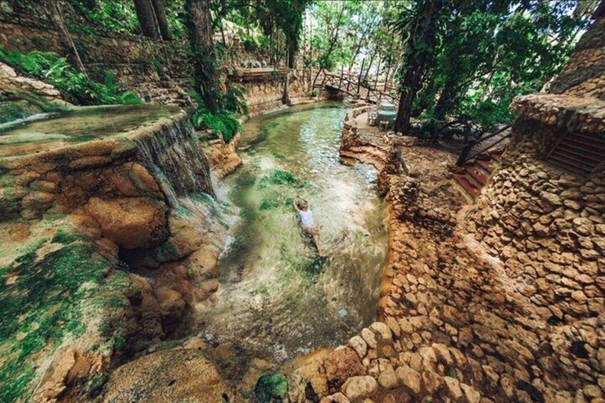 A natural water feature with a small waterfall, surrounded by stone walls and greenery. 5